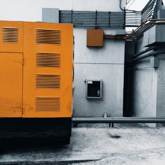 Outdoor power equipment and utility conduit against a concrete wall.
